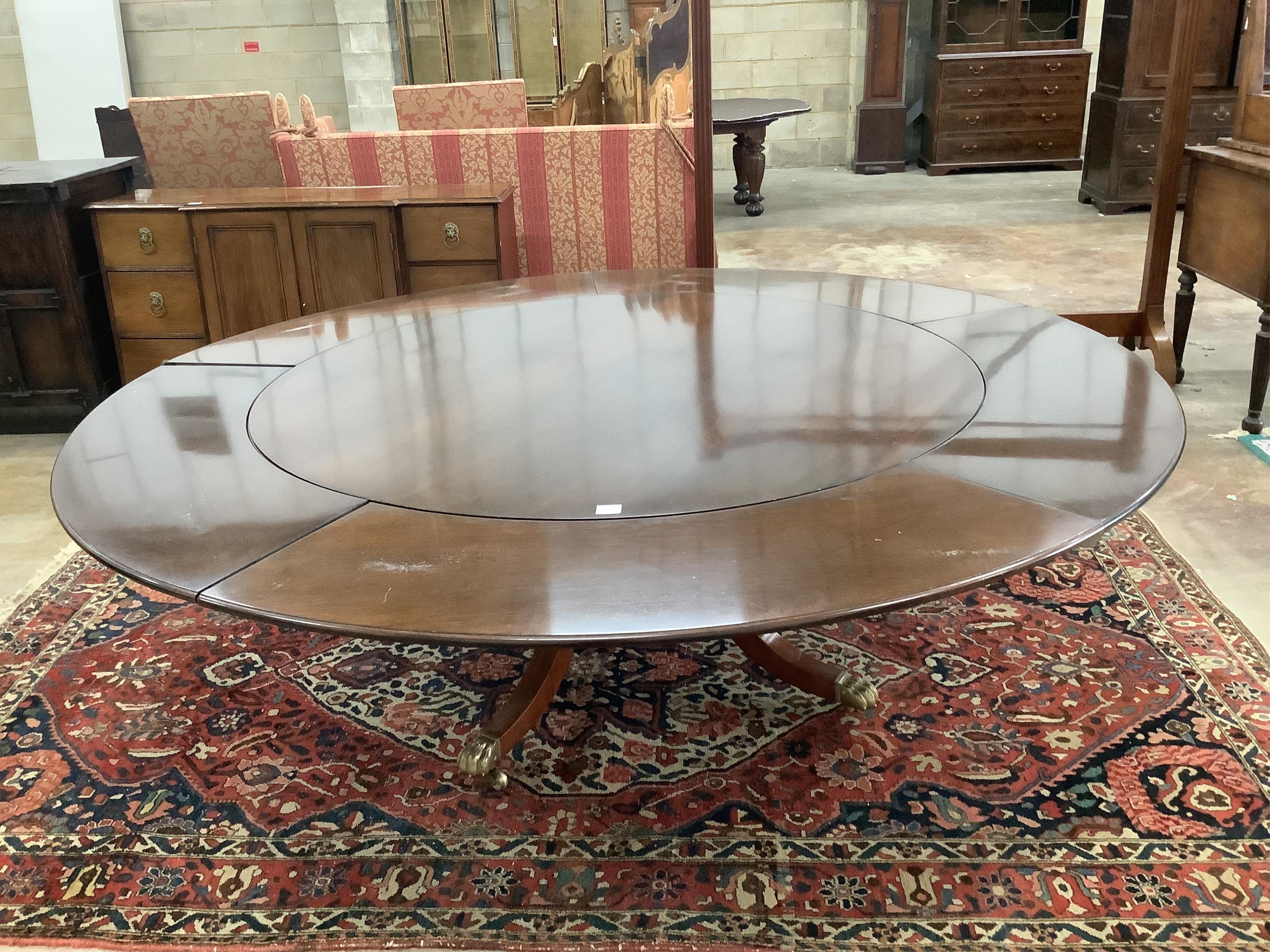 A reproduction George III style mahogany circular segmental extending dining table, diameter 155cm, 230cm extended, height 72cm. Condition - fair